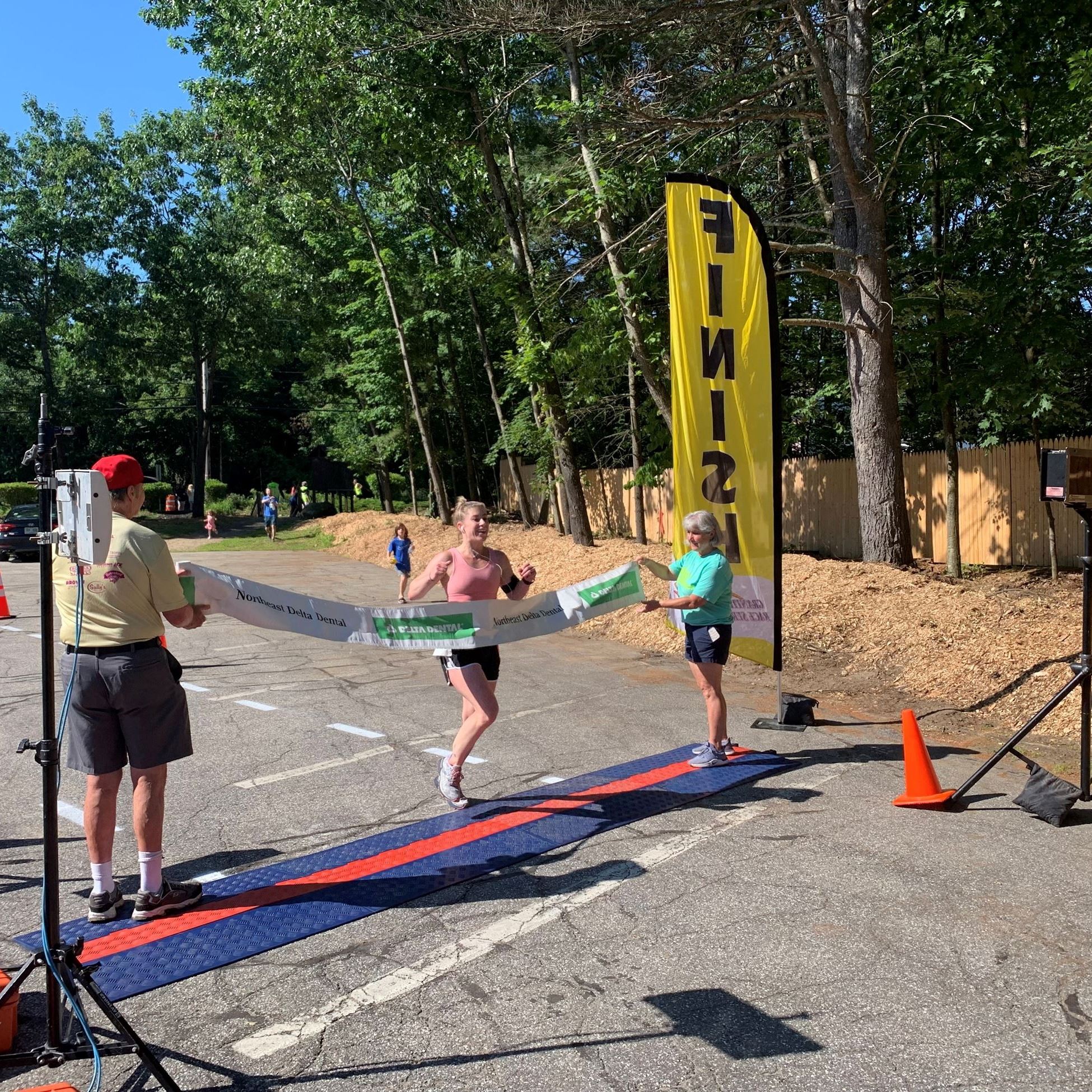 Female winner crossing the finish line and breaking the ribbon
