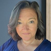 A smiling woman with shoulder length hair and a blue shirt.
